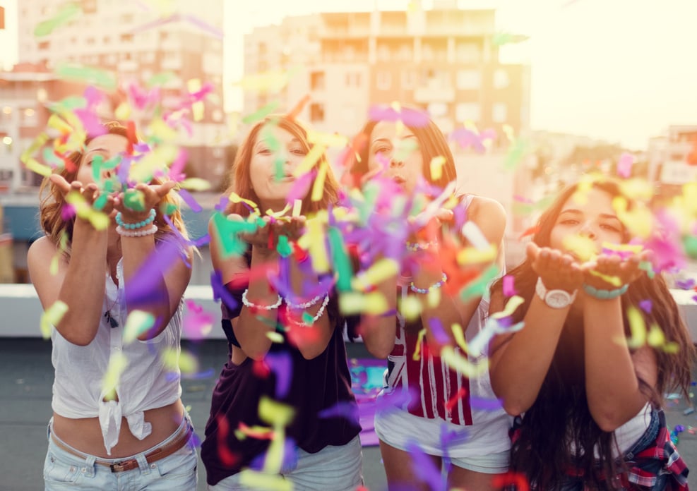 Teenage girls blowing confetti on a rooftop party